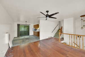 Unfurnished living room with light wood-style floors, ceiling fan, and stairs