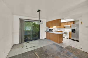 Kitchen with stainless steel fridge with ice dispenser, light countertops, white range with electric cooktop, pendant lighting, and light tile patterned floors