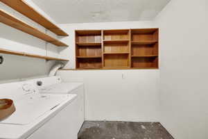 Washroom with washer and clothes dryer and a textured ceiling