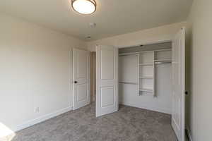 Unfurnished bedroom featuring dark carpet and a closet