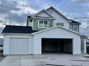 View of front of property with board and batten siding, roof with shingles, and driveway