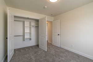 Unfurnished bedroom featuring carpet flooring, a closet, and a textured ceiling