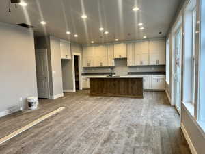 Kitchen featuring recessed lighting, white cabinetry, a center island with sink, and dark wood finished floors