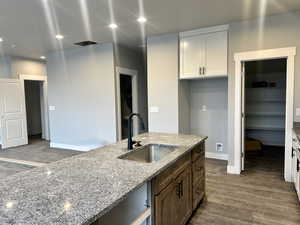 Kitchen with dark wood-style floors, light stone countertops, white cabinetry, and recessed lighting