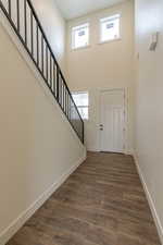 Entrance foyer with a high ceiling, stairs, and dark wood-style flooring
