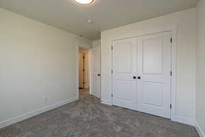 Unfurnished bedroom featuring dark colored carpet and a closet