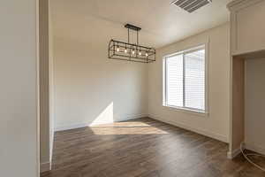 Unfurnished dining area featuring a textured ceiling, dark wood-style flooring, and a chandelier