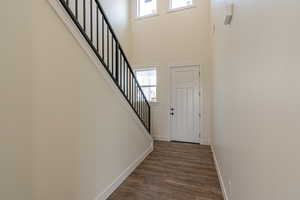 Foyer featuring dark wood-style flooring, stairs, and a towering ceiling