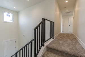 Staircase with recessed lighting and carpet