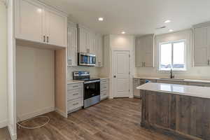 Kitchen with stainless steel appliances, recessed lighting, dark wood finished floors, and light stone counters