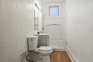 Full bath with light wood-style flooring, vanity, a shower stall, and a textured wall