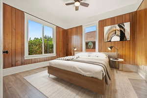Bedroom featuring wood walls, ceiling fan, and wood finished floors