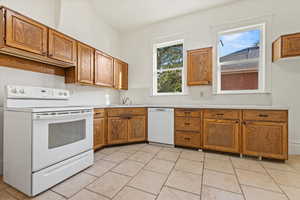 Kitchen with brown cabinets, white appliances, light countertops, and light tile patterned floors