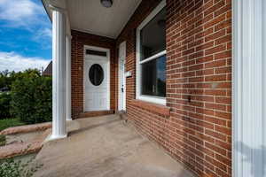 Property entrance featuring brick siding and a porch