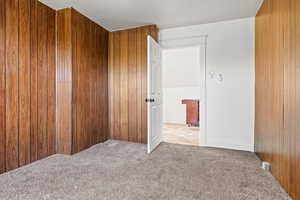 Carpeted spare room featuring wood walls