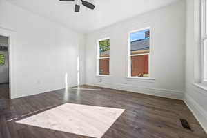 Spare room with plenty of natural light, dark wood finished floors, and a ceiling fan
