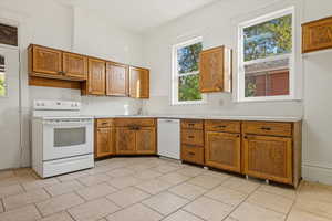 Kitchen with brown cabinets, white appliances, light countertops, and plenty of natural light