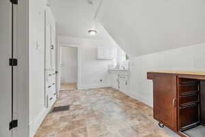 Bathroom with vanity, vaulted ceiling, and stone finish floors