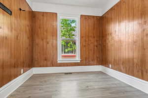 Spare room with light wood-type flooring and wood walls