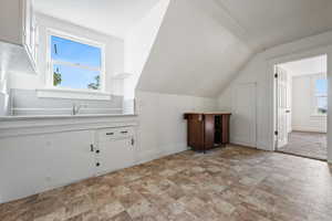 Additional living space with plenty of natural light, stone finish flooring, and lofted ceiling