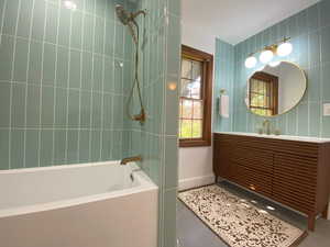 Full bath with bathing tub / shower combination, vanity, and tile walls