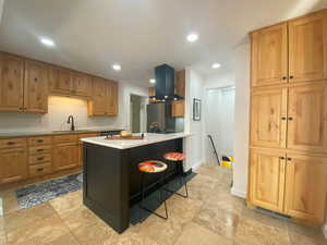 Kitchen featuring recessed lighting, a breakfast bar, island range hood, and decorative backsplash