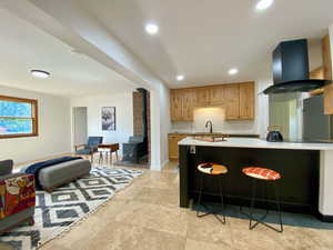 Kitchen featuring a wood stove, island range hood, recessed lighting, open floor plan, and a breakfast bar