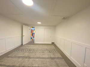 Corridor with a decorative wall, a wainscoted wall, and carpet flooring