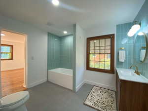 Bathroom with vanity, recessed lighting, bathtub / shower combination, and tile walls