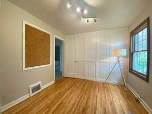 Unfurnished room featuring light wood-type flooring and a decorative wall