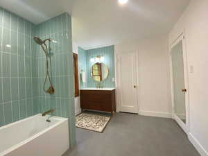 Full bathroom with bathing tub / shower combination, vanity, and dark tile patterned flooring