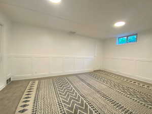 Basement featuring a decorative wall, a wainscoted wall, and carpet flooring