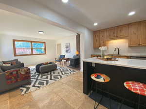 Kitchen with a wood stove, open floor plan, recessed lighting, backsplash, and a breakfast bar area