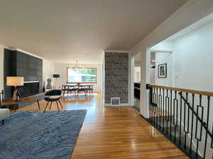 Living room with crown molding, a chandelier, and light wood-style floors