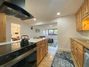 Kitchen with appliances with stainless steel finishes, island range hood, recessed lighting, light stone counters, and light tile patterned flooring