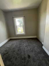 Empty room with dark colored carpet and baseboards