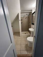 Full bathroom with a stall shower, light tile patterned floors, and lofted ceiling