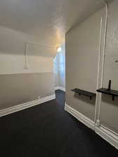 Unfurnished room with a textured ceiling and dark carpet