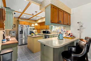 Kitchen with stainless steel appliances, a breakfast bar, hanging light fixtures, a peninsula, and wallpapered walls