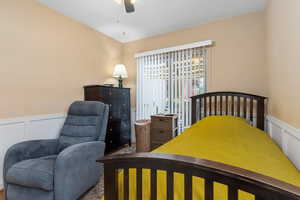 Bedroom with wainscoting, a decorative wall, and a ceiling fan