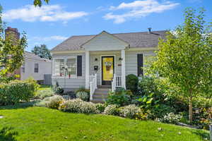 Bungalow-style house featuring a front lawn, roof with shingles, and covered porch