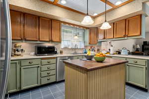 Kitchen featuring a center island, stainless steel appliances, hanging light fixtures, dark tile patterned flooring, and recessed lighting