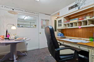 Office area with baseboards and dark carpet