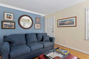 Living area with crown molding and wood finished floors