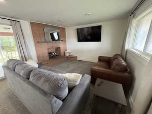 Living room with healthy amount of natural light, a brick fireplace, and carpet flooring