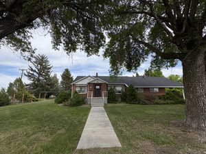 View of front facade featuring brick siding, a chimney, and a front yard