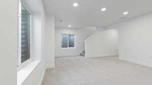 Basement with light carpet, recessed lighting, and stairway