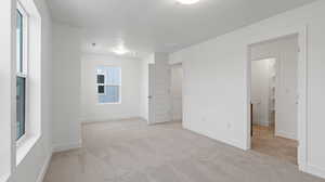 Unfurnished bedroom featuring light carpet and baseboards