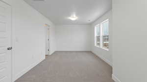 Empty room featuring light colored carpet and baseboards