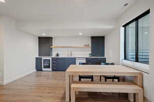 Kitchen featuring blue cabinets, light countertops, light wood-style floors, recessed lighting, and wine cooler